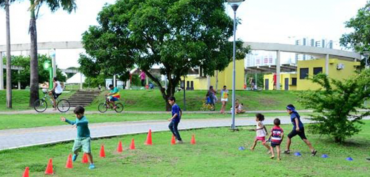 Área verde com crianças brincando e correndo no gramado 